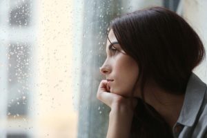 smutna kobieta patrzy w okno